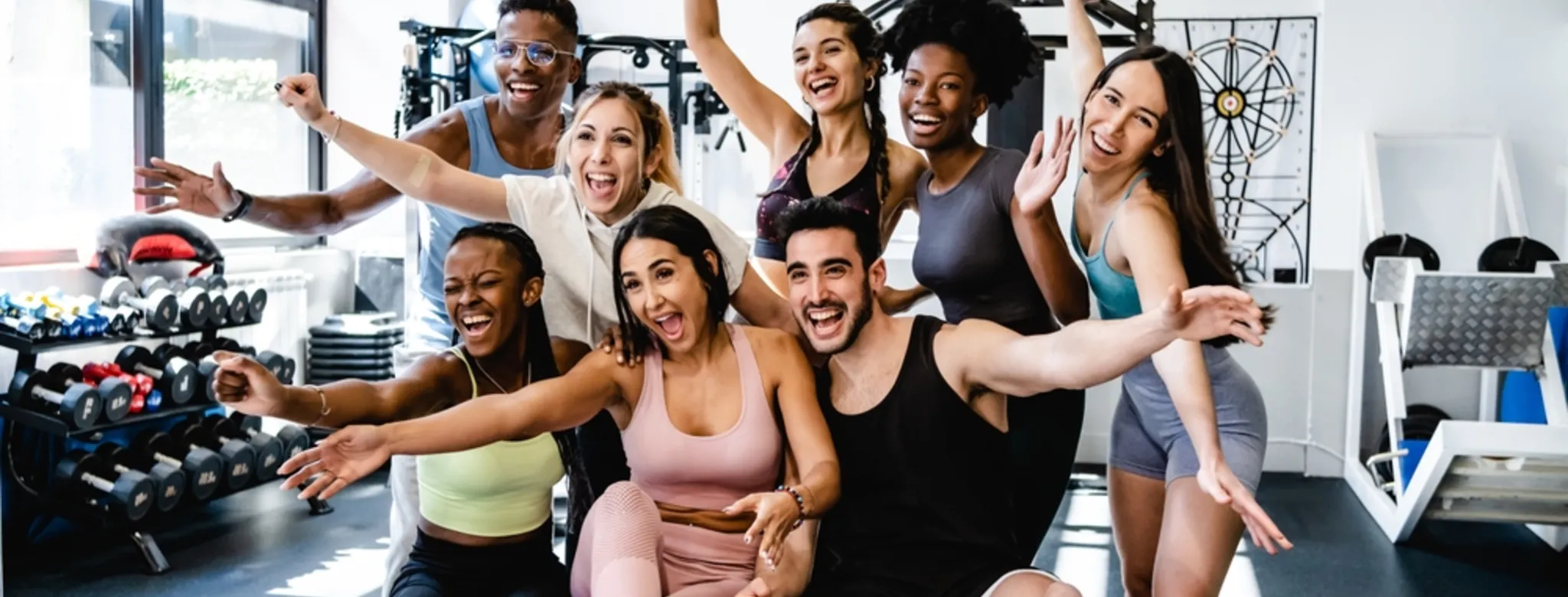 Eight people smiling posing for a picture at a gym